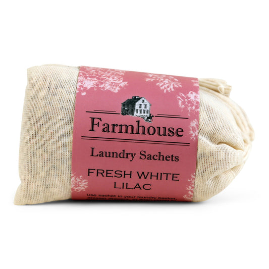 A bundle of beige linen sachets with a pink label that reads 'Farmhouse Laundry Sachets FRESH WHITE LILAC'.