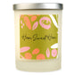 A white soy wax candle with a label that has 'Home Sweet Home' written on it and colorful abstract shapes.