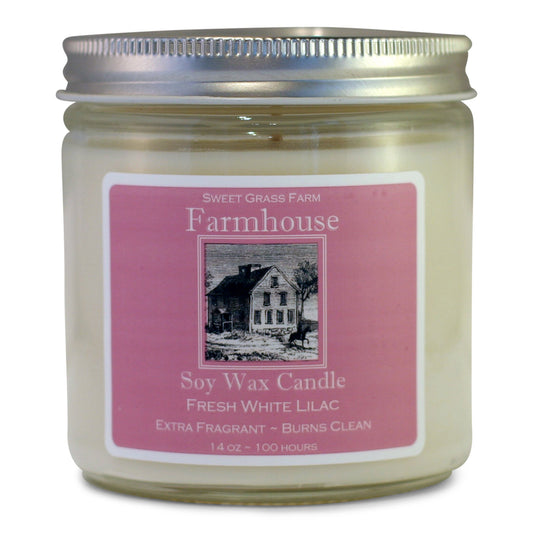 A soy wax candle jar with a label that reads 'Farmhouse Soy Wax Candle, Fresh White Lilac, Extra Fragrant - Burns Clean', with a picture of a house and the brand name 'Sweet Grass Farm'.