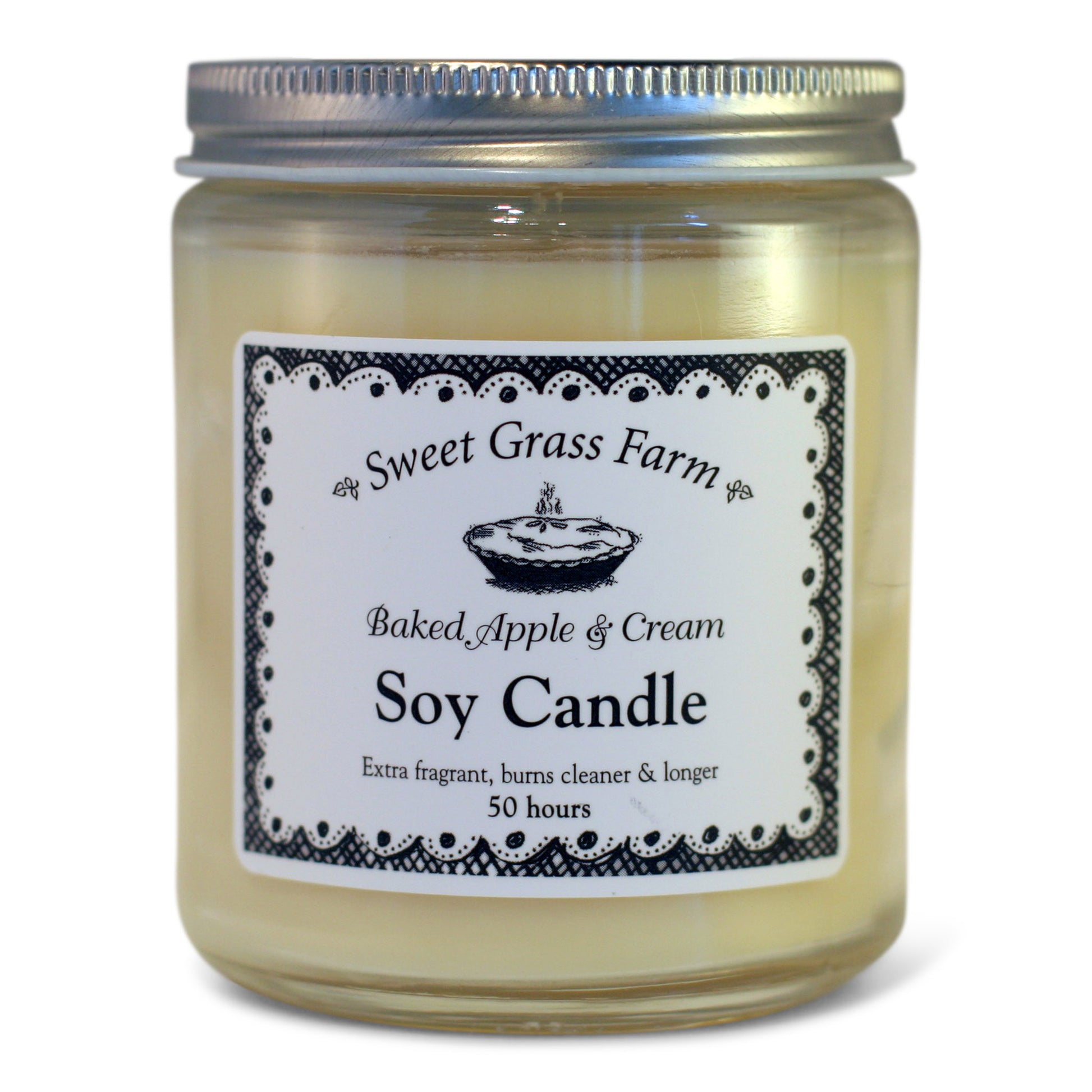 A soy wax candle in a clear glass jar with a label reading 'Sweet Grass Farm Baked Apple & Cream Soy Candle', with a definition stating 'Extra fragrant, burns cleaner & longer 50 hours'.