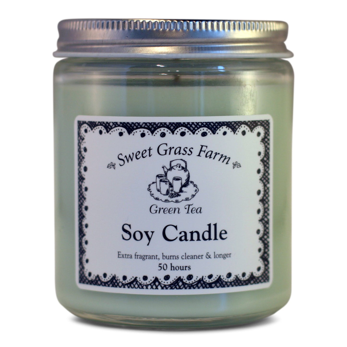 A soy wax candle in a clear glass jar with a label reading 'Sweet Grass Farm Green Tea Soy Candle', with a definition stating 'Extra fragrant, burns cleaner & longer 50 hours'.
