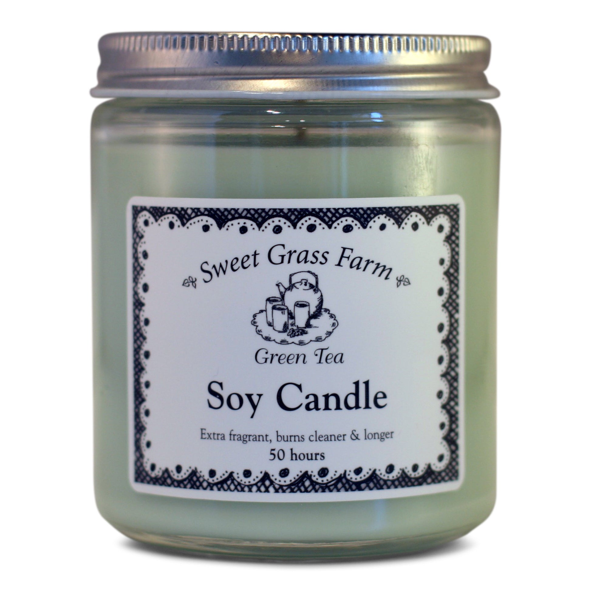 A soy wax candle in a clear glass jar with a label reading 'Sweet Grass Farm Green Tea Soy Candle', with a definition stating 'Extra fragrant, burns cleaner & longer 50 hours'.